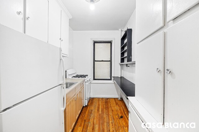 kitchen featuring light countertops, dark wood finished floors, white cabinets, and white appliances