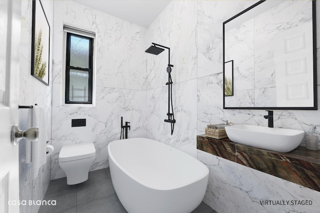 full bath with a sink, a freestanding tub, toilet, and tile walls