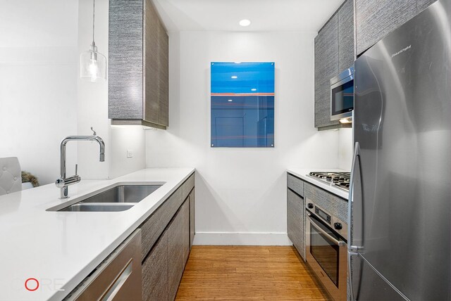 305 W 16th St Unit 4E, New York City, NY 10011 - kitchen with appliances with stainless steel finishes, a sink, light wood-style flooring, light countertops, and baseboards