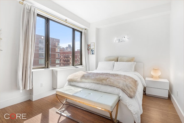 305 W 16th St Unit 4E, New York City, NY 10011 - bedroom with wood finished floors, baseboards, and a city view