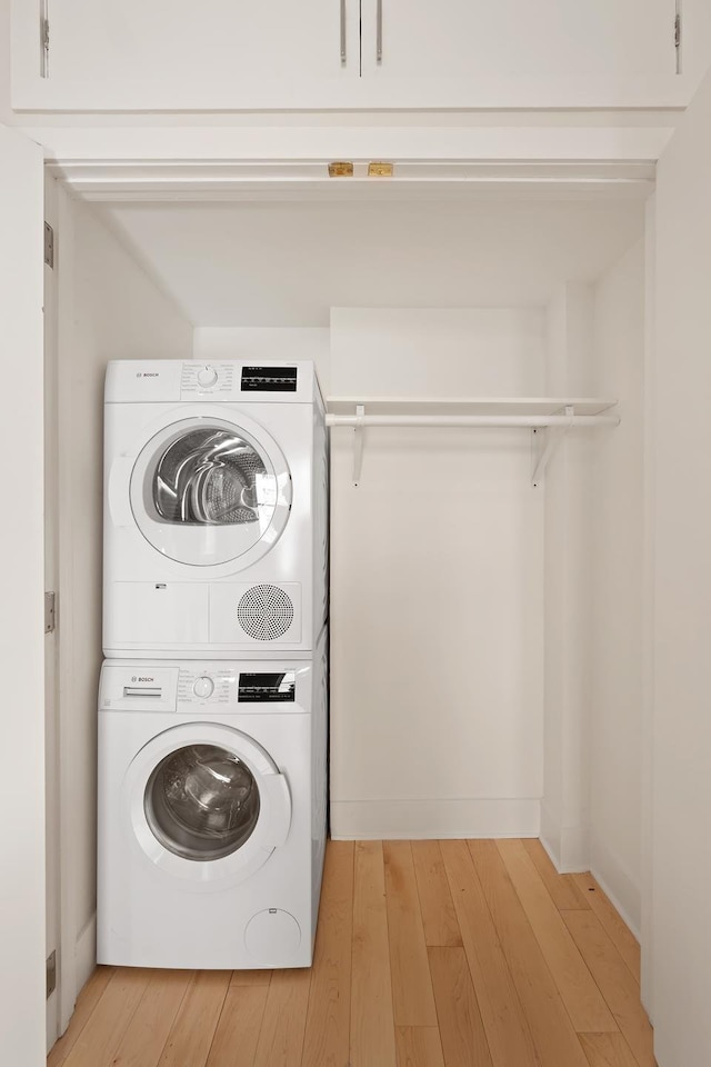 laundry room with estacked washer and dryer and light wood-style flooring