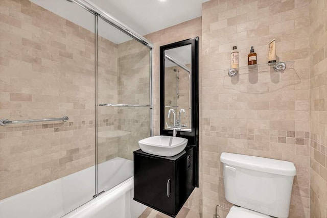 169 E 69th St Unit 19A, New York City, NY 10021 - bathroom featuring vanity, combined bath / shower with glass door, tile walls, and toilet