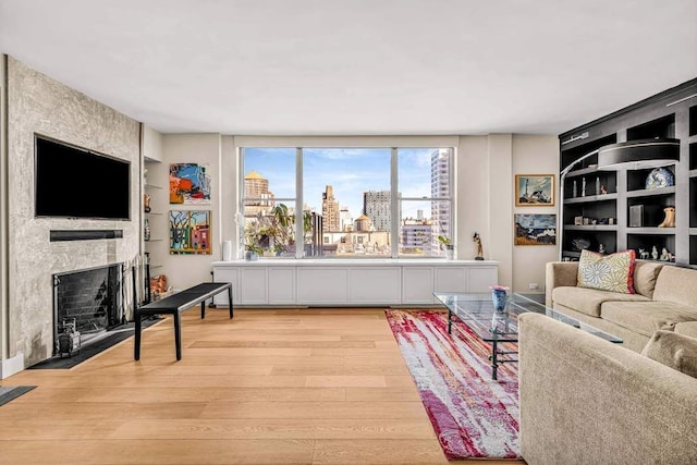 169 E 69th St Unit 19A, New York City, NY 10021 - living area featuring built in features, light wood-style flooring, a fireplace, and a view of city