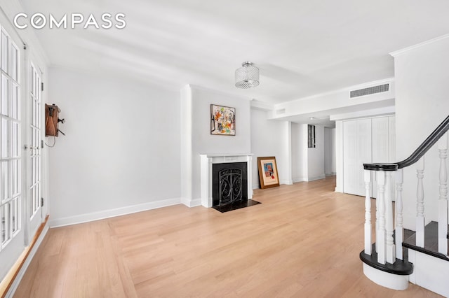 57 E 73rd St Unit 1/2, New York City, NY 10021 - unfurnished living room featuring stairs, a fireplace with flush hearth, light wood-type flooring, and baseboards