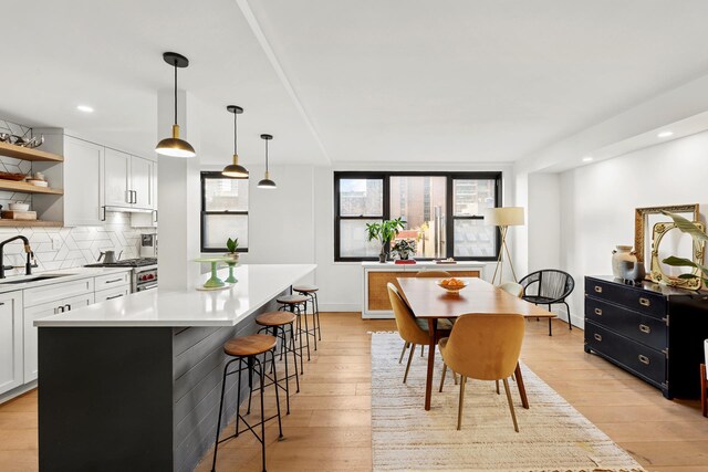kitchen with white cabinetry, tasteful backsplash, open shelves, a sink, and light wood finished floors