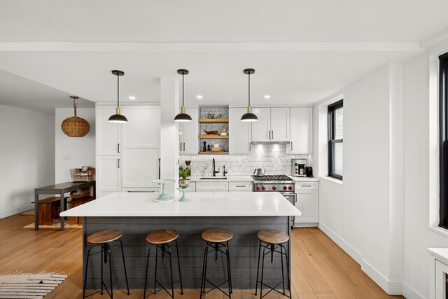 kitchen featuring a sink, white cabinets, a kitchen bar, and tasteful backsplash