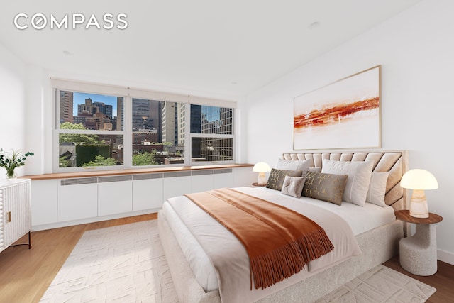 bedroom featuring a view of city and light wood finished floors