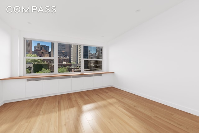 spare room featuring baseboards, a city view, and light wood-type flooring