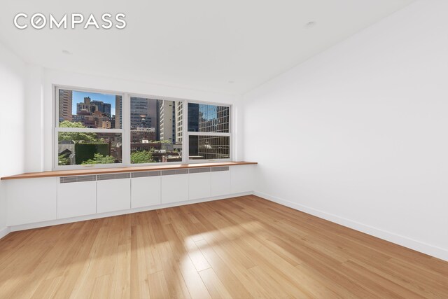 221 E 50th St Unit 6D/7D, New York City, NY 10022 - spare room with light wood-type flooring, a city view, and baseboards