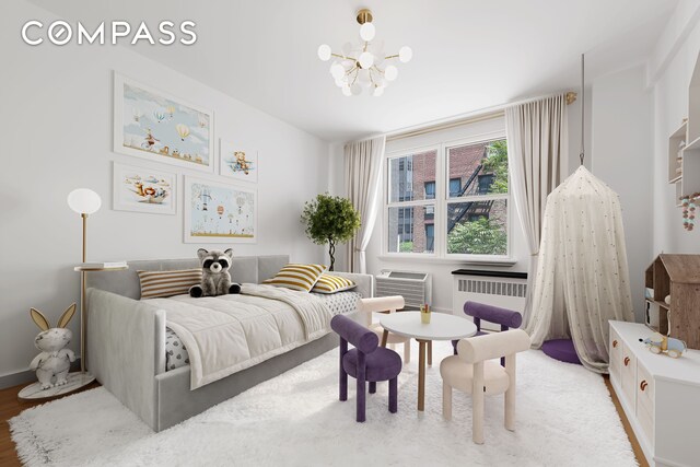 221 E 50th St Unit 6D/7D, New York City, NY 10022 - bedroom featuring a chandelier, radiator heating unit, baseboards, and wood finished floors