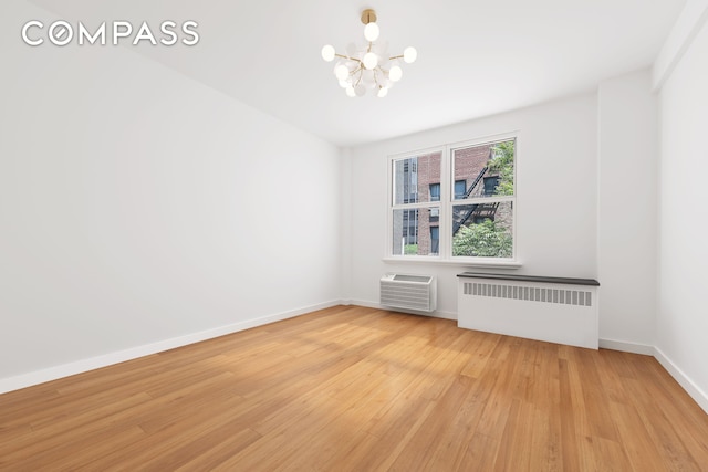 221 E 50th St Unit 6D/7D, New York City, NY 10022 - empty room with radiator heating unit, a chandelier, light wood-style floors, and a wall mounted air conditioner