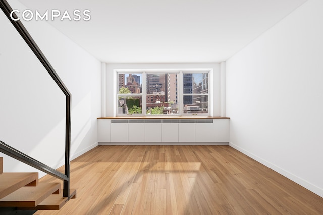 interior space with stairway, radiator, baseboards, and light wood-type flooring
