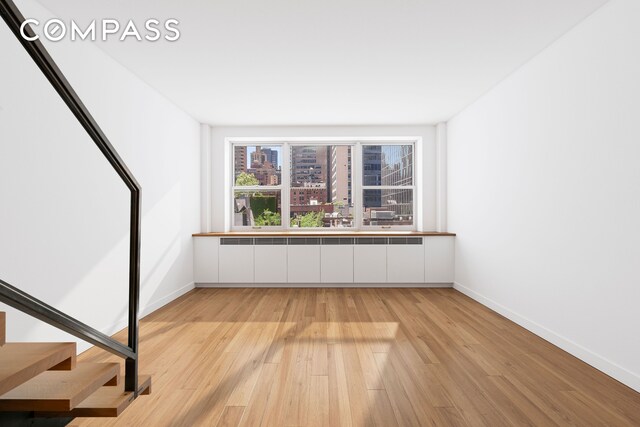 221 E 50th St Unit 6D/7D, New York City, NY 10022 - unfurnished room with light wood-style floors, baseboards, and stairway
