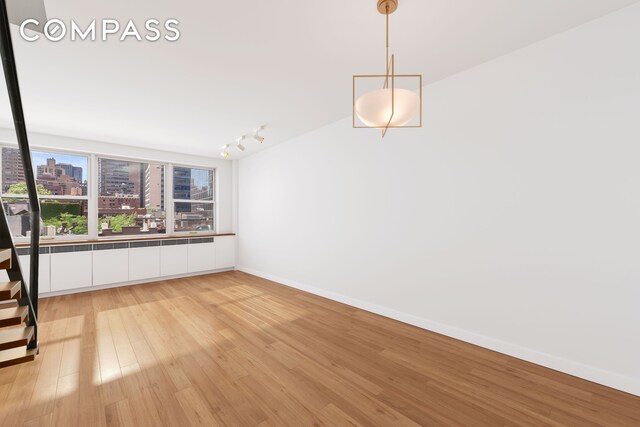 221 E 50th St Unit 6D/7D, New York City, NY 10022 - unfurnished room with light wood-style flooring, a view of city, baseboards, and track lighting