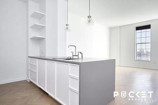 184 Kent Ave Unit C-614, New York City, NY 11249 - kitchen with a sink, open shelves, white cabinetry, built in features, and decorative light fixtures
