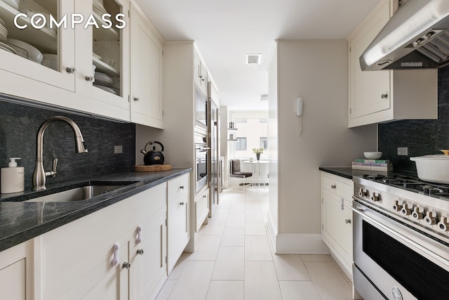 kitchen with range with gas stovetop, under cabinet range hood, a sink, and decorative backsplash