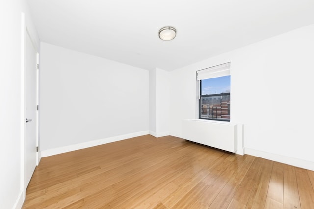 unfurnished room with light wood-type flooring and baseboards