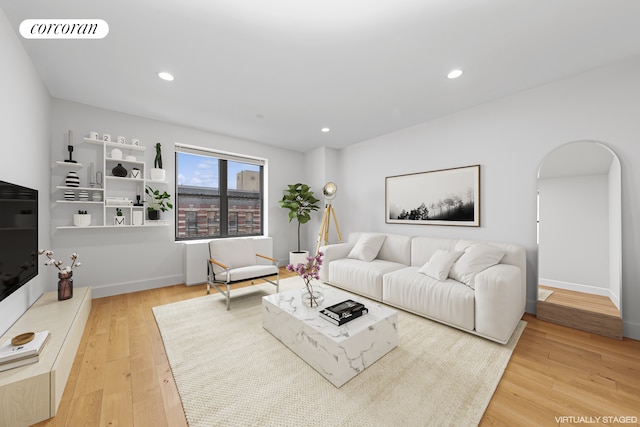 living area featuring arched walkways, wood finished floors, recessed lighting, and baseboards