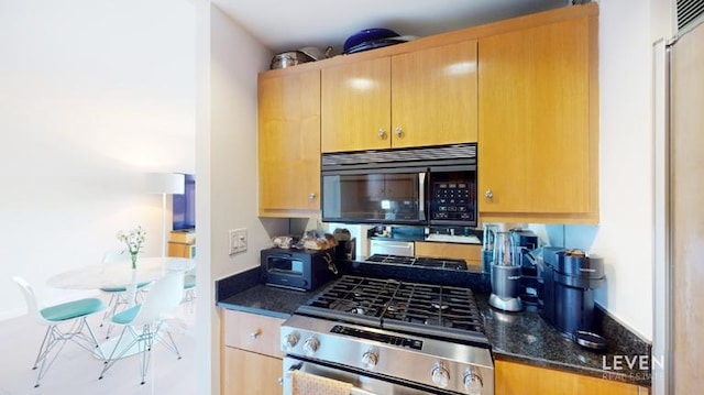 kitchen featuring dark stone counters, stainless steel gas stove, and black microwave