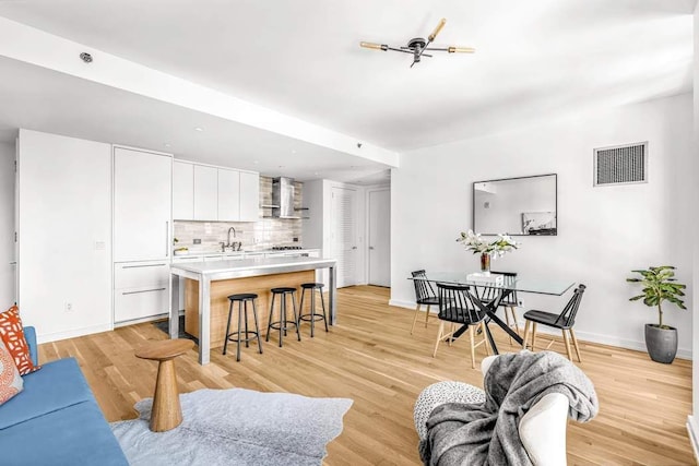 living room featuring visible vents, baseboards, and light wood finished floors