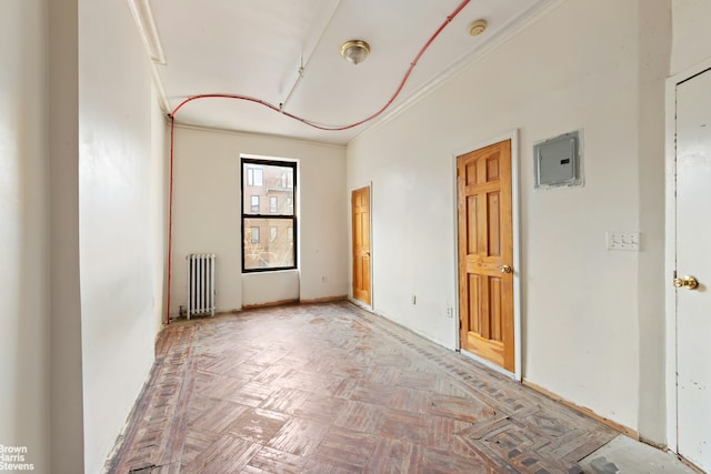empty room with radiator, electric panel, and crown molding