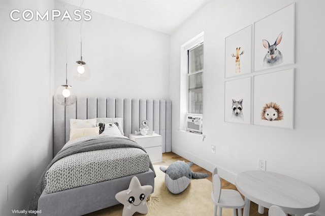 bedroom with radiator heating unit, cooling unit, and wood finished floors