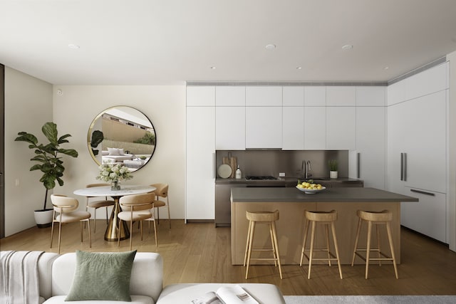 kitchen featuring a kitchen island, dark countertops, modern cabinets, a kitchen breakfast bar, and white cabinets