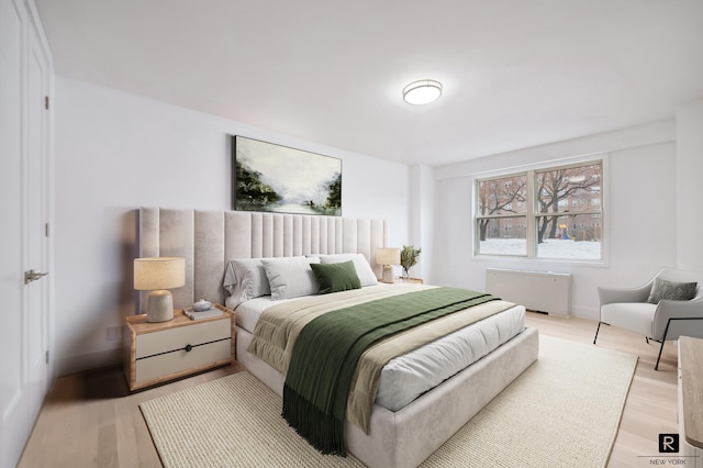 bedroom with radiator heating unit and light wood-style floors