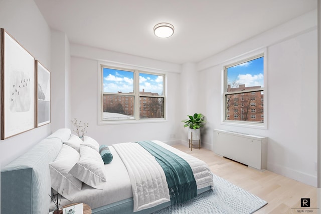 bedroom with light wood finished floors, multiple windows, and baseboards