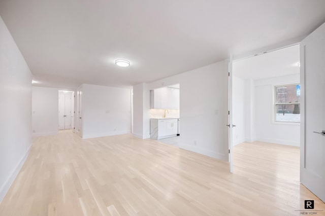 interior space with a sink, light wood-style flooring, and baseboards