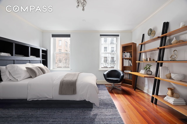 bedroom with baseboards, crown molding, and wood finished floors