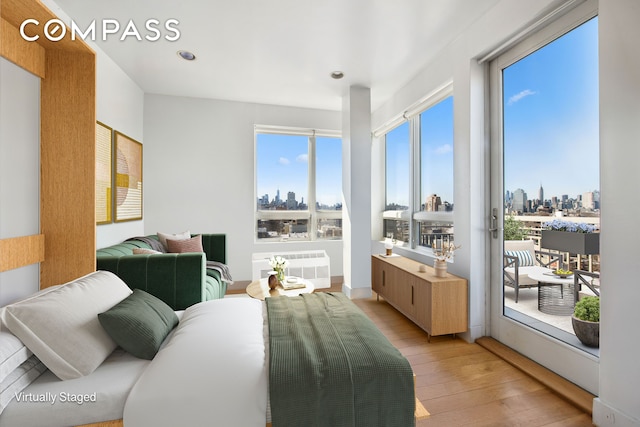 bedroom with recessed lighting, access to outside, a city view, and light wood-type flooring