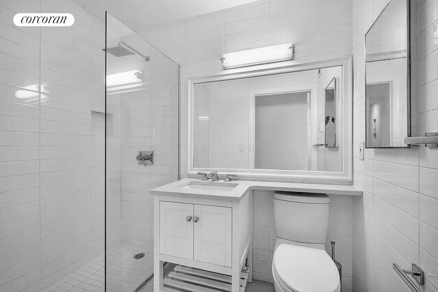 bathroom featuring tile walls, vanity, a walk in shower, and toilet
