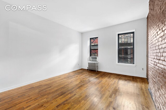 433 W 54th St Unit 1, New York City, NY 10019 - unfurnished room with radiator heating unit, hardwood / wood-style flooring, and baseboards