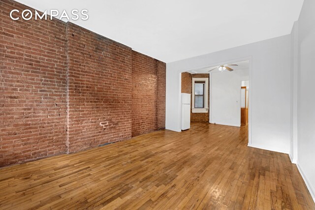 433 W 54th St Unit 1, New York City, NY 10019 - empty room with hardwood / wood-style floors, brick wall, baseboards, and a ceiling fan
