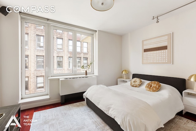 125 W 21st St Unit 12A, New York City, NY 10011 - bedroom featuring radiator heating unit, wood finished floors, and track lighting