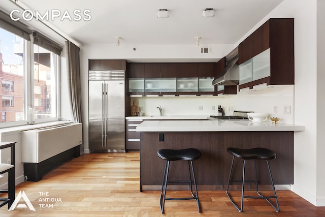 125 W 21st St Unit 12A, New York City, NY 10011 - kitchen with high quality fridge, light countertops, a sink, a peninsula, and light wood finished floors