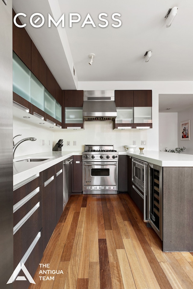 125 W 21st St Unit 12A, New York City, NY 10011 - kitchen featuring appliances with stainless steel finishes, ventilation hood, modern cabinets, and wine cooler