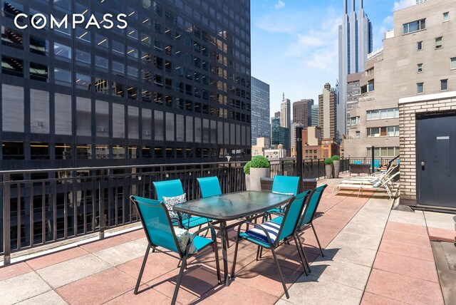view of patio / terrace featuring a view of city, fence, and outdoor dining area