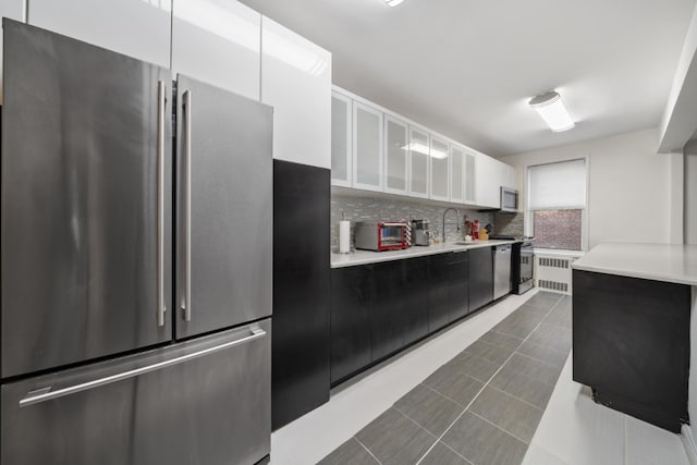 79-10 34th Ave Unit 3S, New York City, NY 11372 - kitchen featuring appliances with stainless steel finishes, radiator, light countertops, and white cabinetry