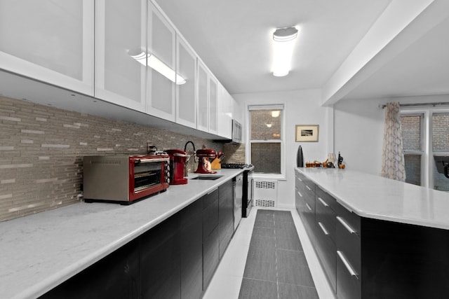79-10 34th Ave Unit 3S, New York City, NY 11372 - kitchen with dark cabinetry, a sink, light countertops, and backsplash