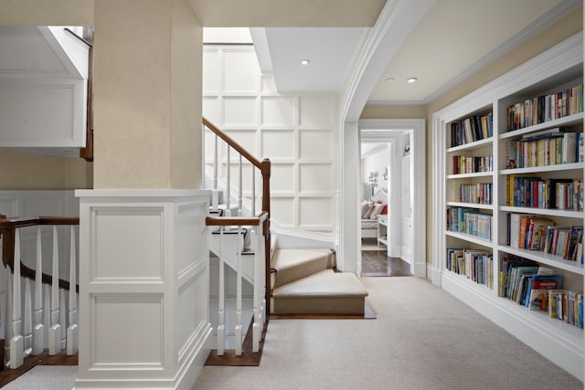 333 E 68th Street Penthouse, New York City, NY 10065 - staircase featuring built in features, a decorative wall, carpet, and ornamental molding