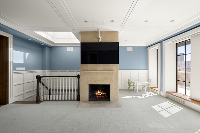 333 E 68th Street Penthouse, New York City, NY 10065 - unfurnished living room featuring carpet, a decorative wall, a high end fireplace, ornamental molding, and a wainscoted wall