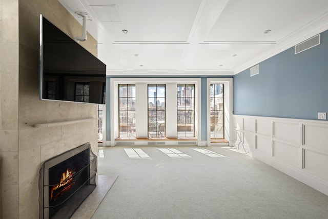 333 E 68th Street Penthouse, New York City, NY 10065 - unfurnished living room with carpet flooring, a tiled fireplace, crown molding, a wainscoted wall, and coffered ceiling
