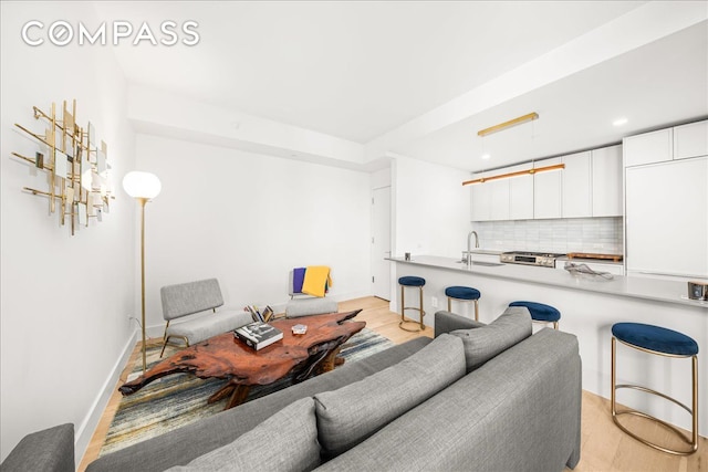 living room featuring baseboards, light wood finished floors, and recessed lighting