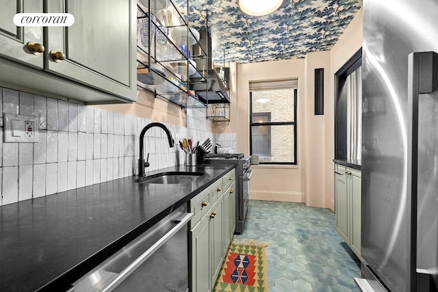 kitchen with stainless steel appliances, a sink, dark tile patterned floors, baseboards, and tasteful backsplash