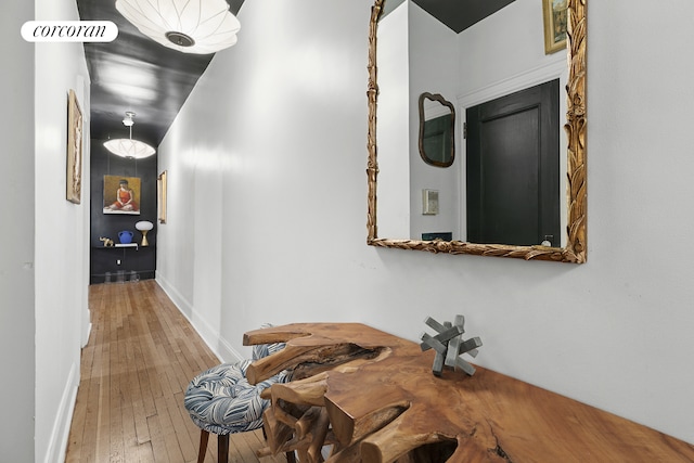 corridor with wood-type flooring, baseboards, and visible vents