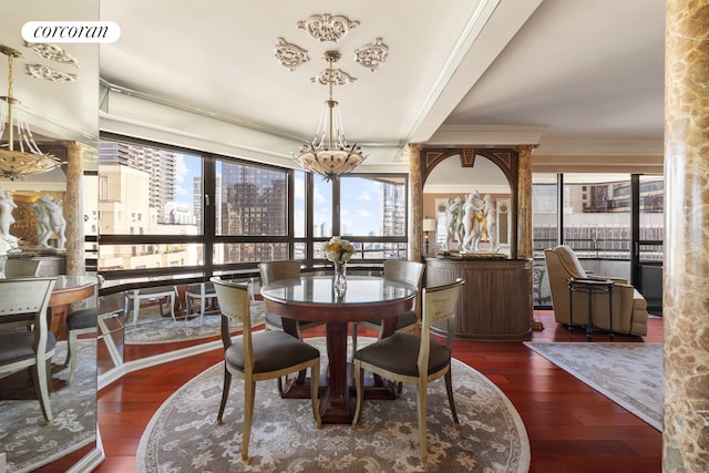 dining space with crown molding, a view of city, wood finished floors, and a chandelier