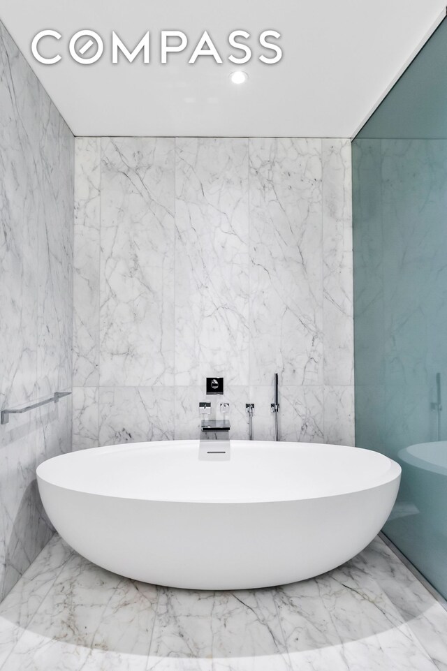 520 W 28th St Unit 18, New York City, NY 10001 - bathroom featuring stone wall, a freestanding tub, and recessed lighting
