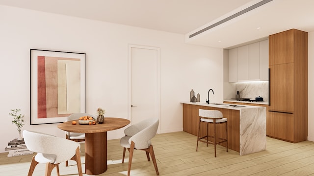 31-16 21st St Unit 3-A, New York City, NY 11106 - kitchen featuring modern cabinets, a breakfast bar, a peninsula, light countertops, and light wood-style floors